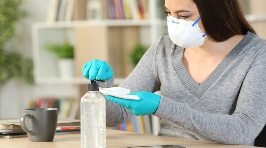 Image of teen wearing mask and gloves putting sanitizer on a cloth showing Contamination fears of Adolescent teens with OCD