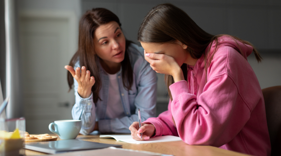 Angry mother asking teen daughter about poor academic performance