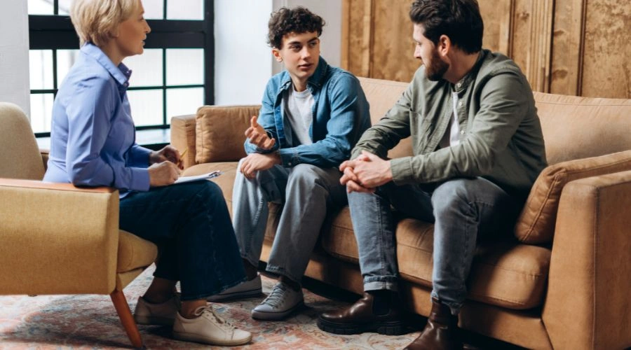 Image of a father and teenage son talking to a therapist