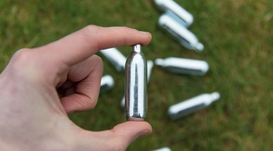Image of a whippet in a hand with numerous whippets on the ground - Inhalant Abuse