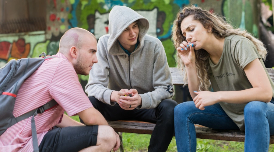 Image of a female teen smoking pot as two male teens look on - Mental Health Disorders Associated with Drug Abuse
