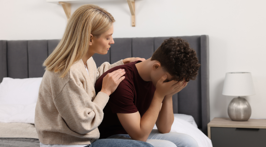 Mother consoling her depressed son at home