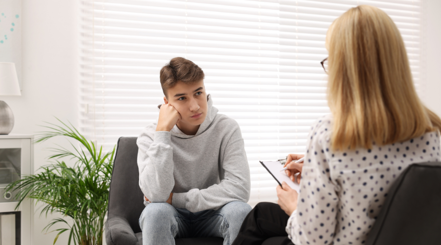 Psychologist having session with teenage boy in her private consulting