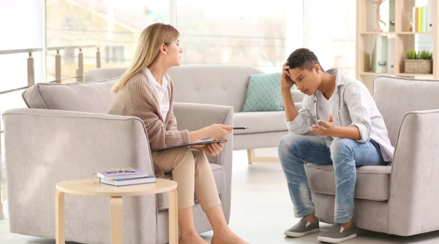 Image of a male teen in treatment talking to a counselor - Teen Addiction Treatment
