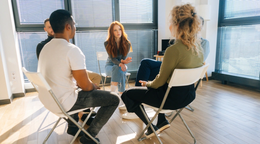 Image of teen participating in a Narcotics Anonymous meeting, listening to peers share experiences with addiction and recovery