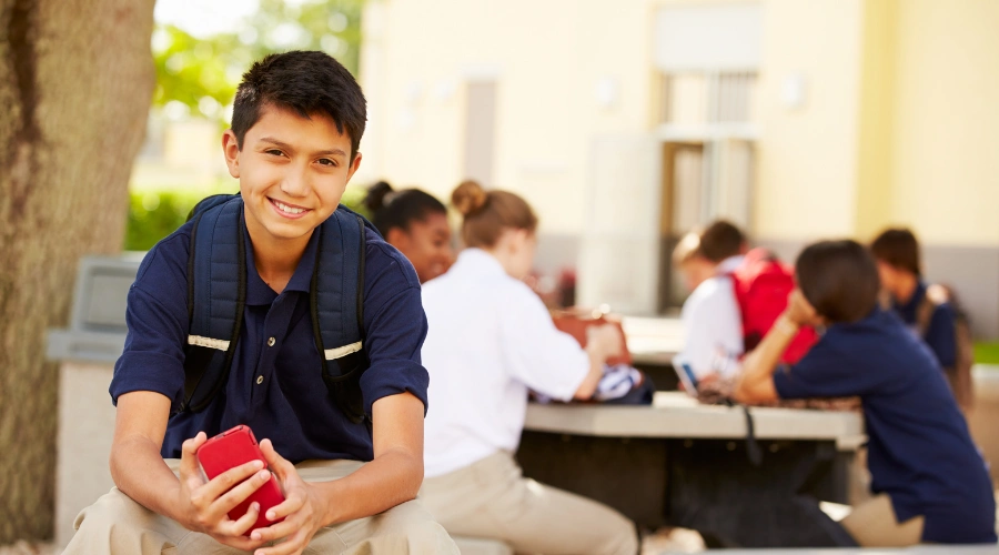 Image of a happy teen in school, sitting in front of other male and female teens at a table - Do Boarding Schools for Troubled Teens Treat Mental Health - Artemis Adolescent Healing Center