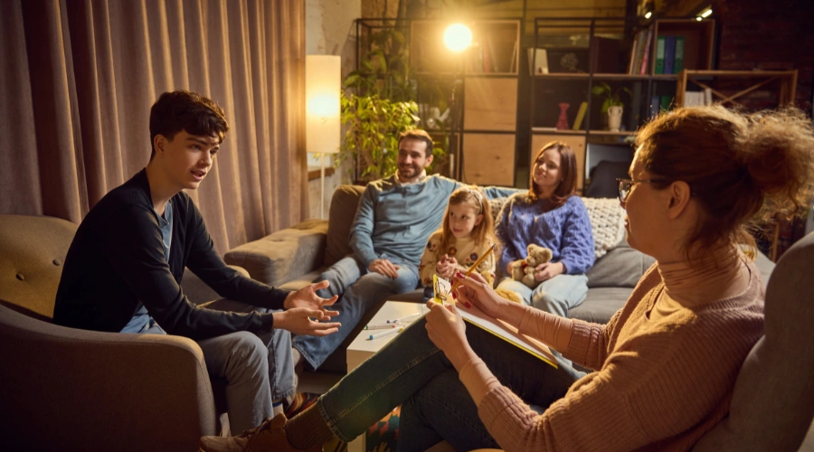 Image of a family sitting together with a therapist, discussing and working through a teen’s behavioral challenges in a supportive setting