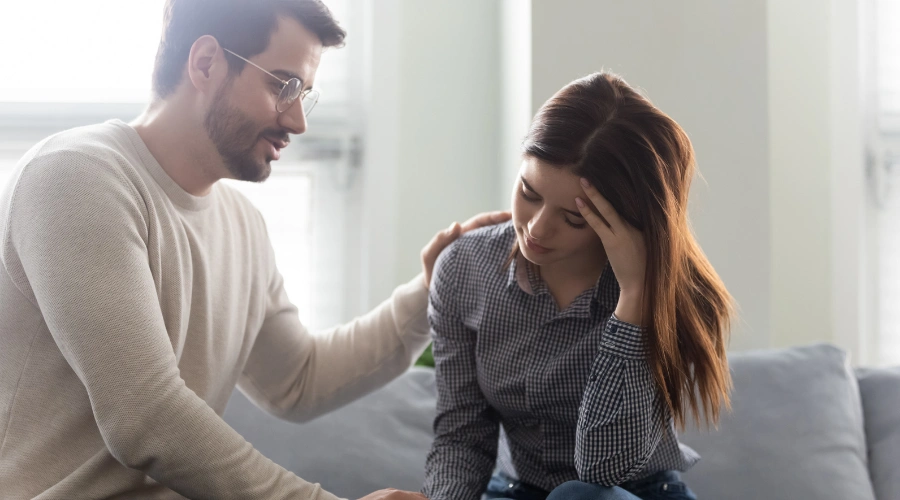 Image of a depressed teen sitting pensively while talking with her father