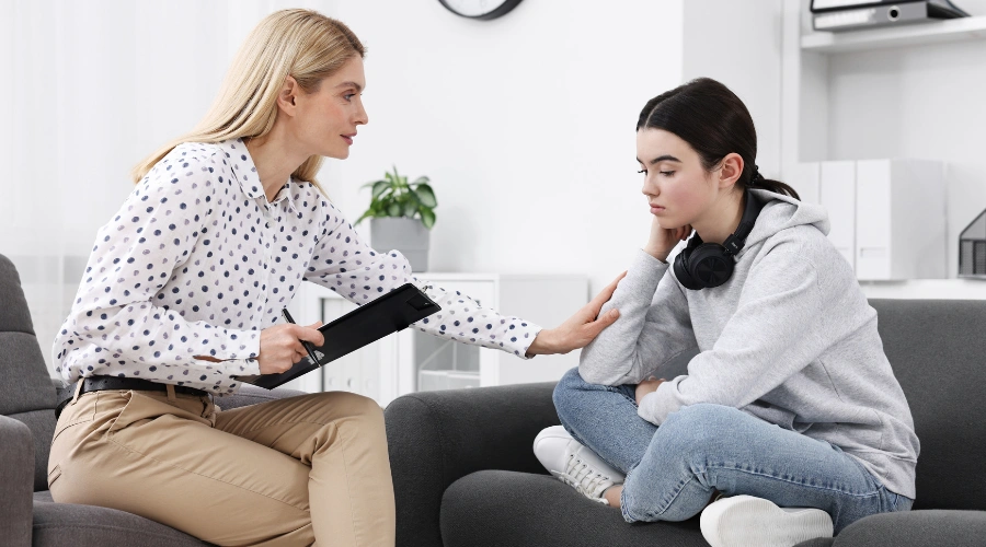 Image of trauma-informed therapist listening to a teen during a supportive mental health session