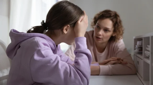 Image of a mother talking to her distraught teen, who is holding her hand over her face - Teen Disruptive Mood Dysregulation Disorder Treatment - Artemis Adolescent Healing Center