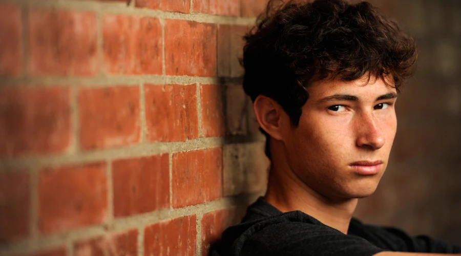 A teen considering rehab looks at the camera with concern