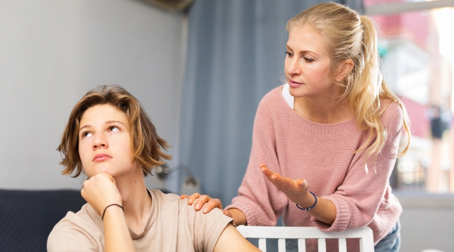 Image of teen displaying passive aggressive behavior by avoiding eye contact and withdrawing from parent during conversation