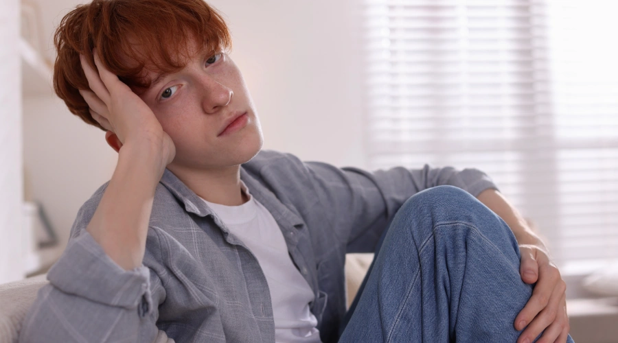 Image of a bored male teen about to engage in risky behavior - Signs of Risky Behavior in Teens - Artemis Adolescent Healing Center