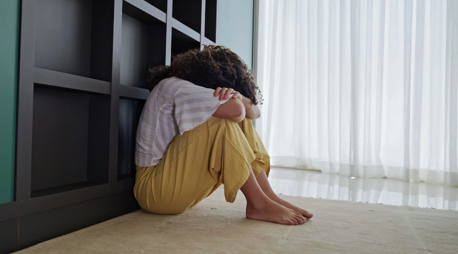 Image of a distraught female teen sitting with face on elbows and knees - Signs of Emotional Dysregulation in Teens - Artemis Adolescent Healing Center