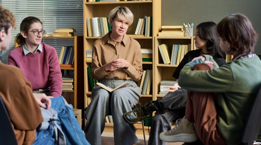 Image of a group of diverse teenagers sitting in a circle with a therapist