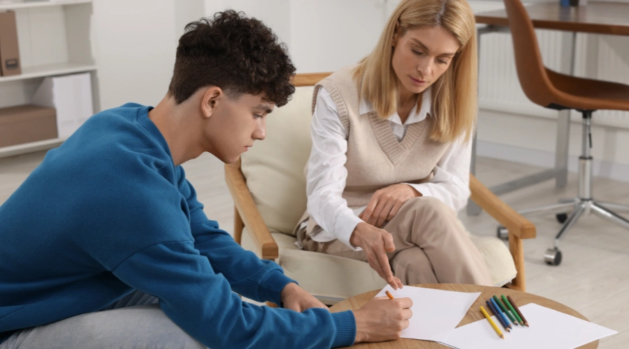 Image of a licensed art therapist guiding an adolescent through a creative therapy exercise