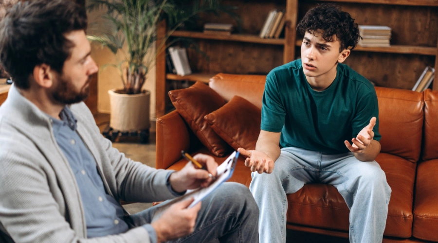 Image of a teenage boy speaking openly with a male therapist shows the concept of Cigna Coverage for Teen Addiction Treatment Support