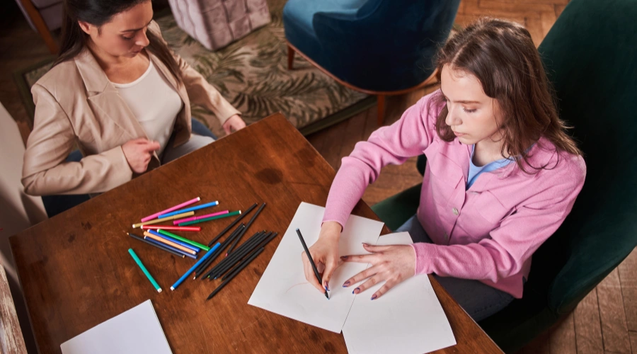 Image of a teenage girl engaged in artwork during an art therapy session for emotional healing